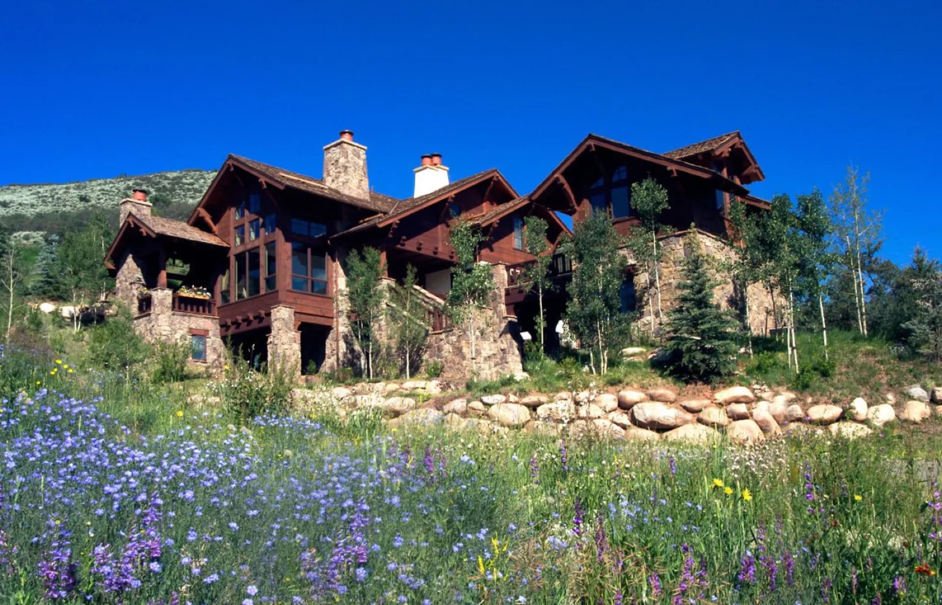 Stone-and-timber custom mountain home with wildflower meadow